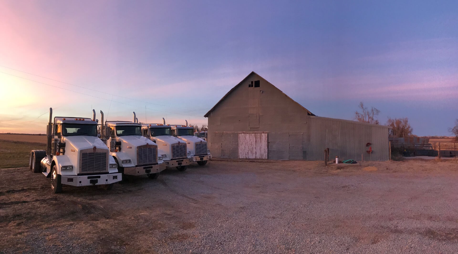 Trucks and a barn at sunset